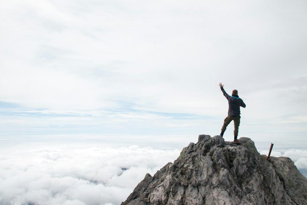 Climber celebrating on a summit above the clouds